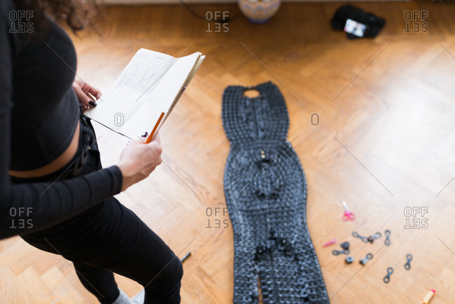 woman creating a costume from pieces of leather woven together