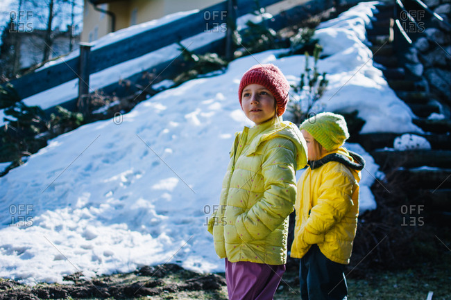 Two children wearing yellow anoraks standing outside in the snow