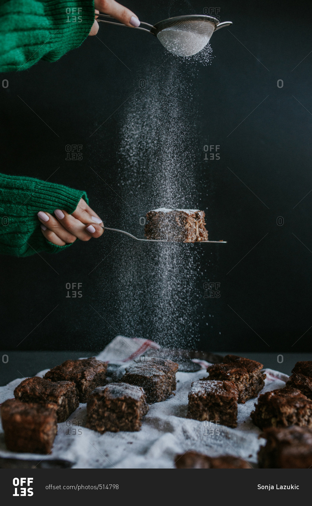 Person sifting confectioner\'s sugar on homemade vegan brownies