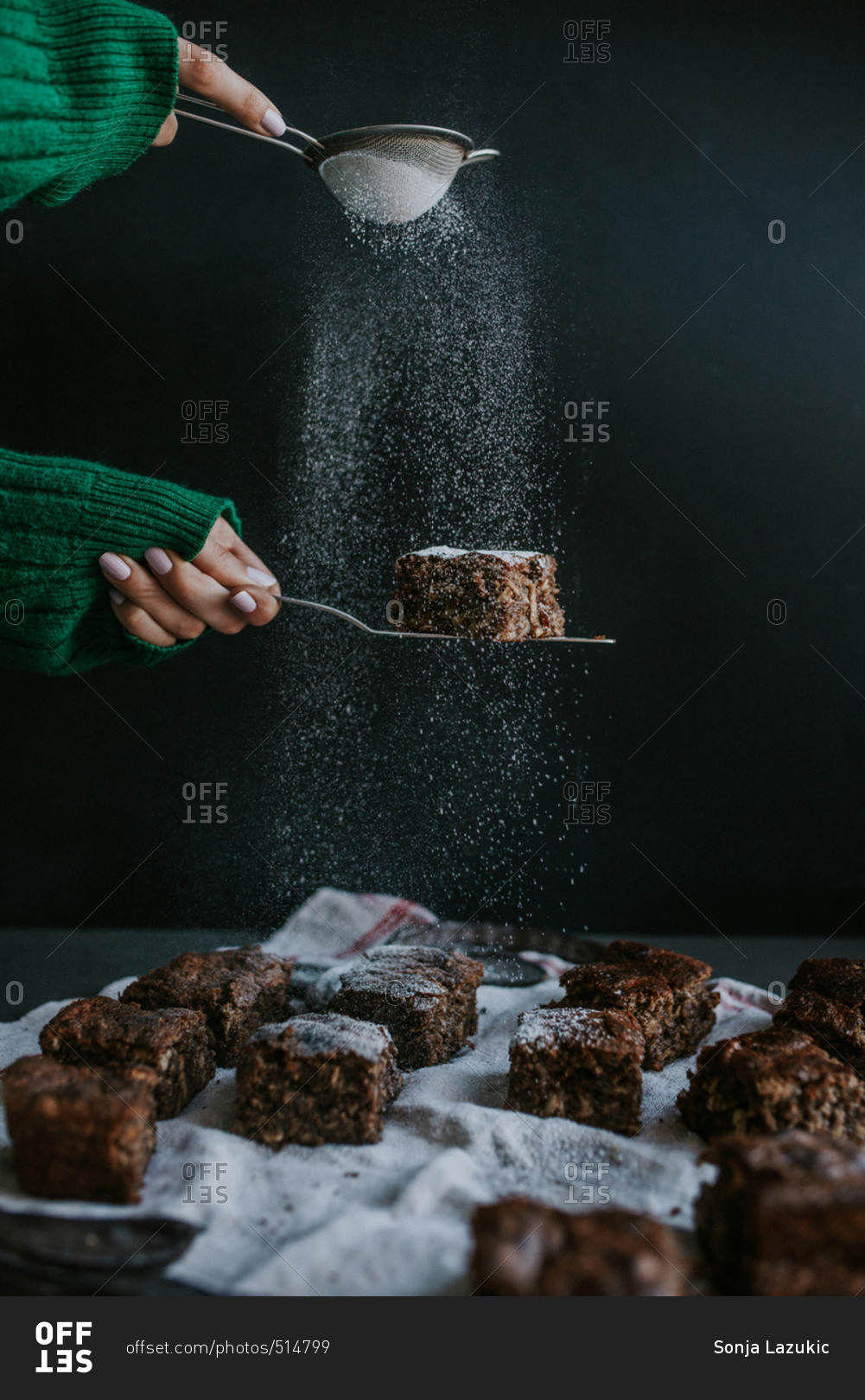 Person dusting powdered sugar on homemade vegan brownies