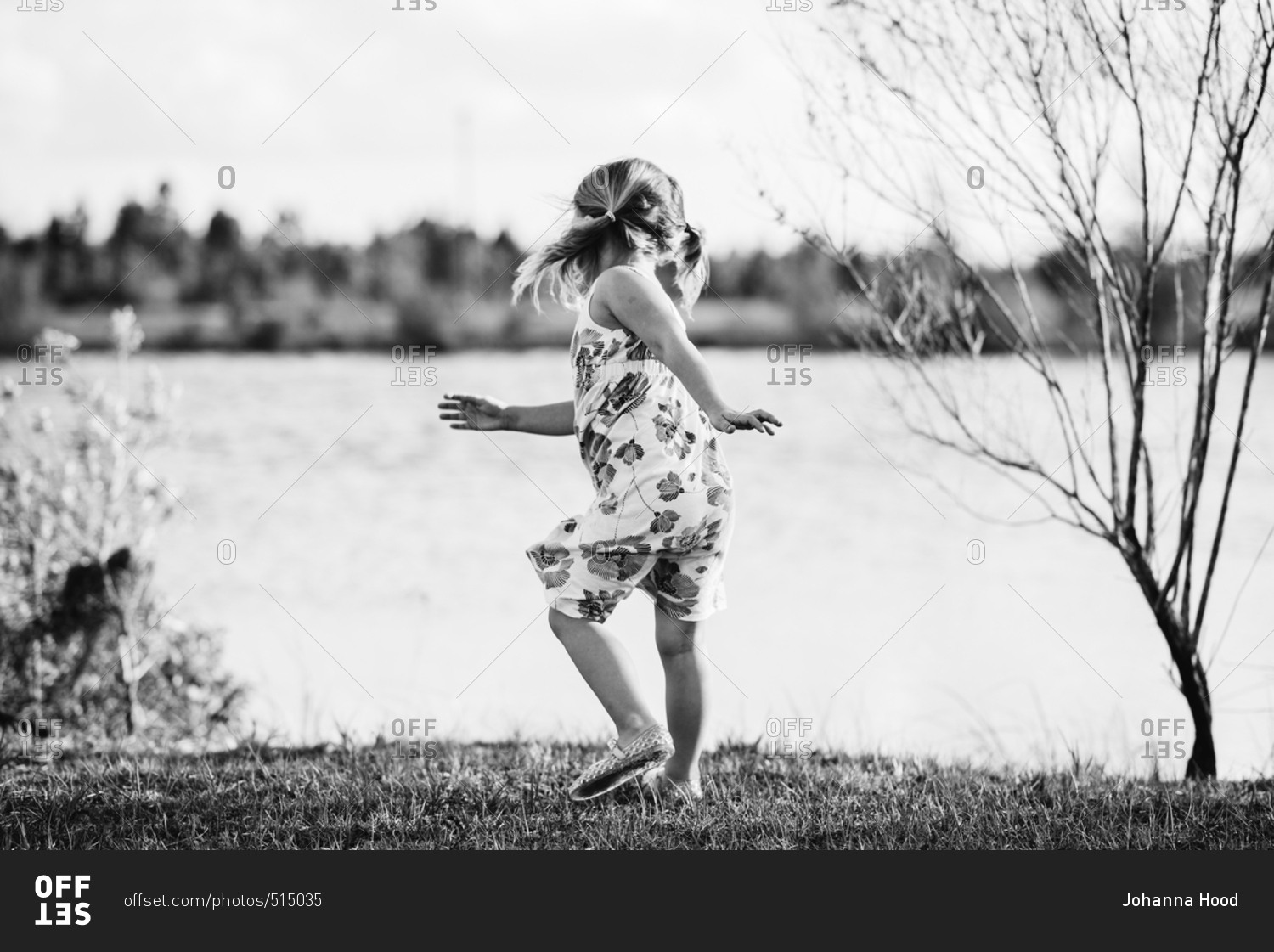 Little girl with pigtails by a lake in black and white stock photo OFFSET