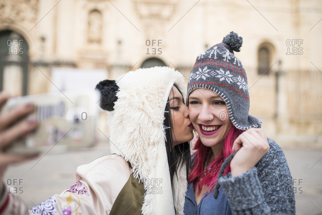 Two young women taking self portraits in European Jaen cathedral square, Spain.