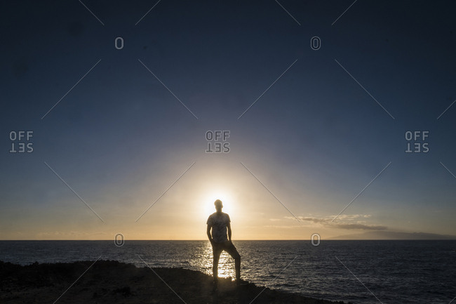 Man backlit by sun on coast