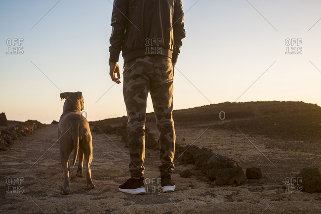Dog and man stand in barren setting