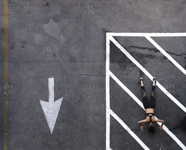 Aerial view of Pacific Islander woman doing push-ups in parking lot
