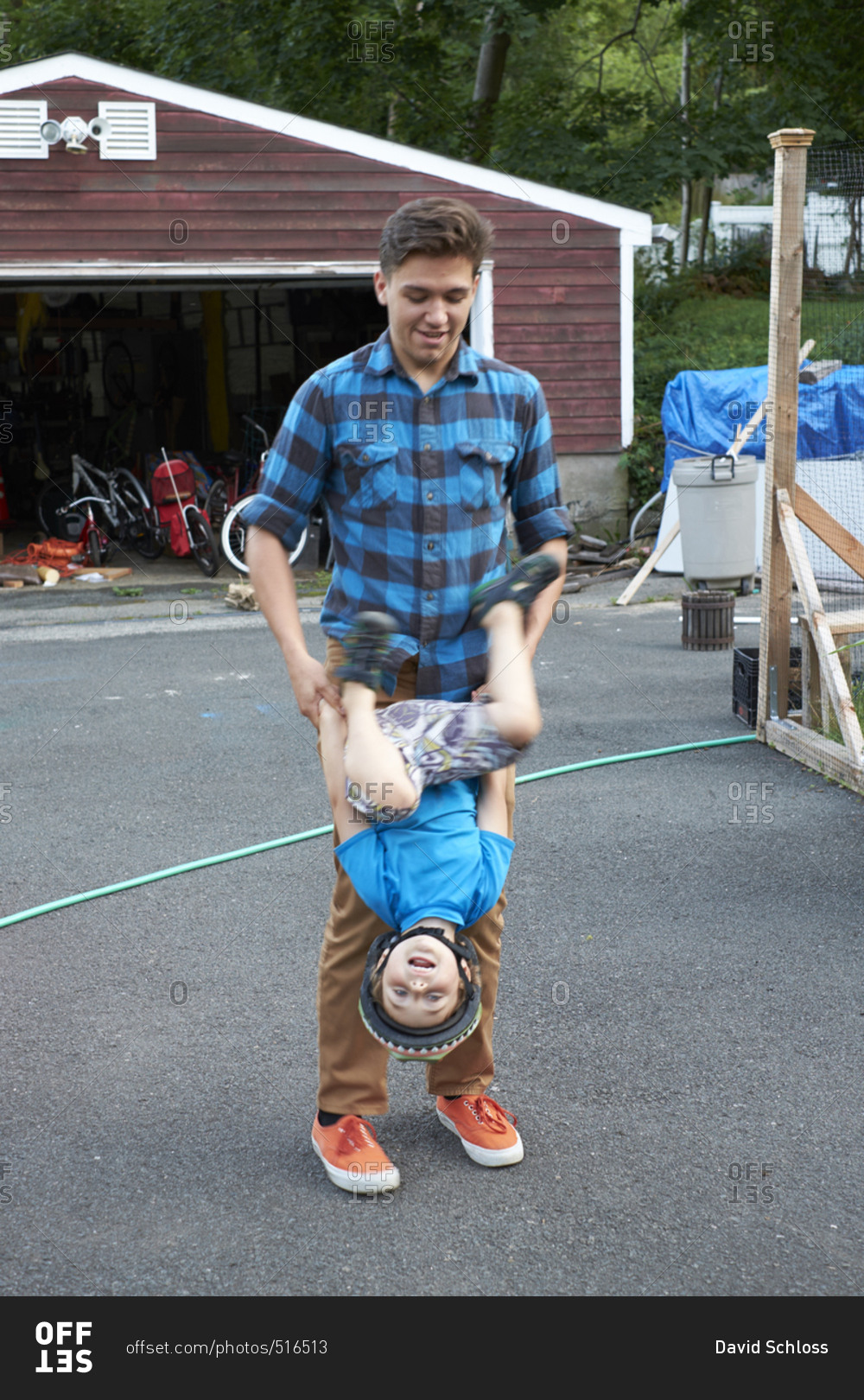Man holding child\'s arms as he flips upside down