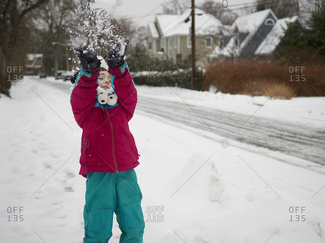 Boy playing in snow in suburban neighborhood