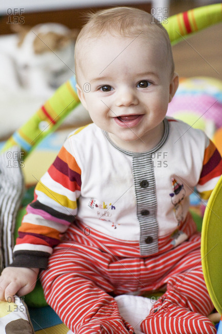Baby boy sitting up alone playing on quilt in play room