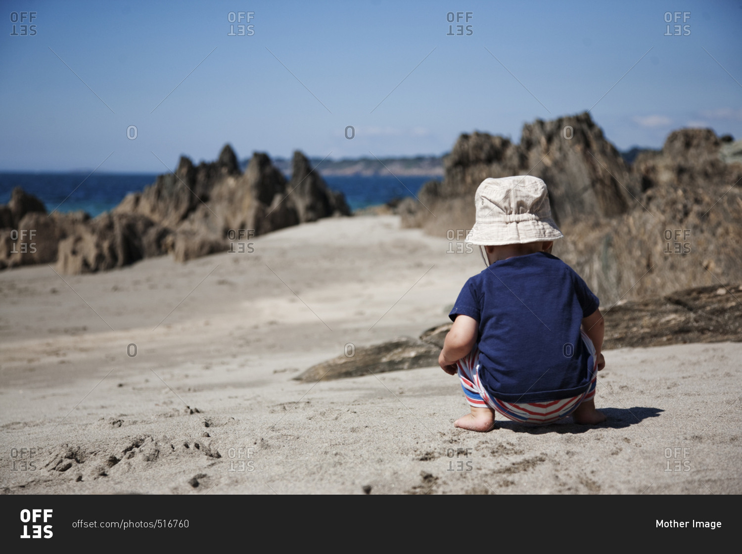 Baby boy playing on beach facing away from camera, France