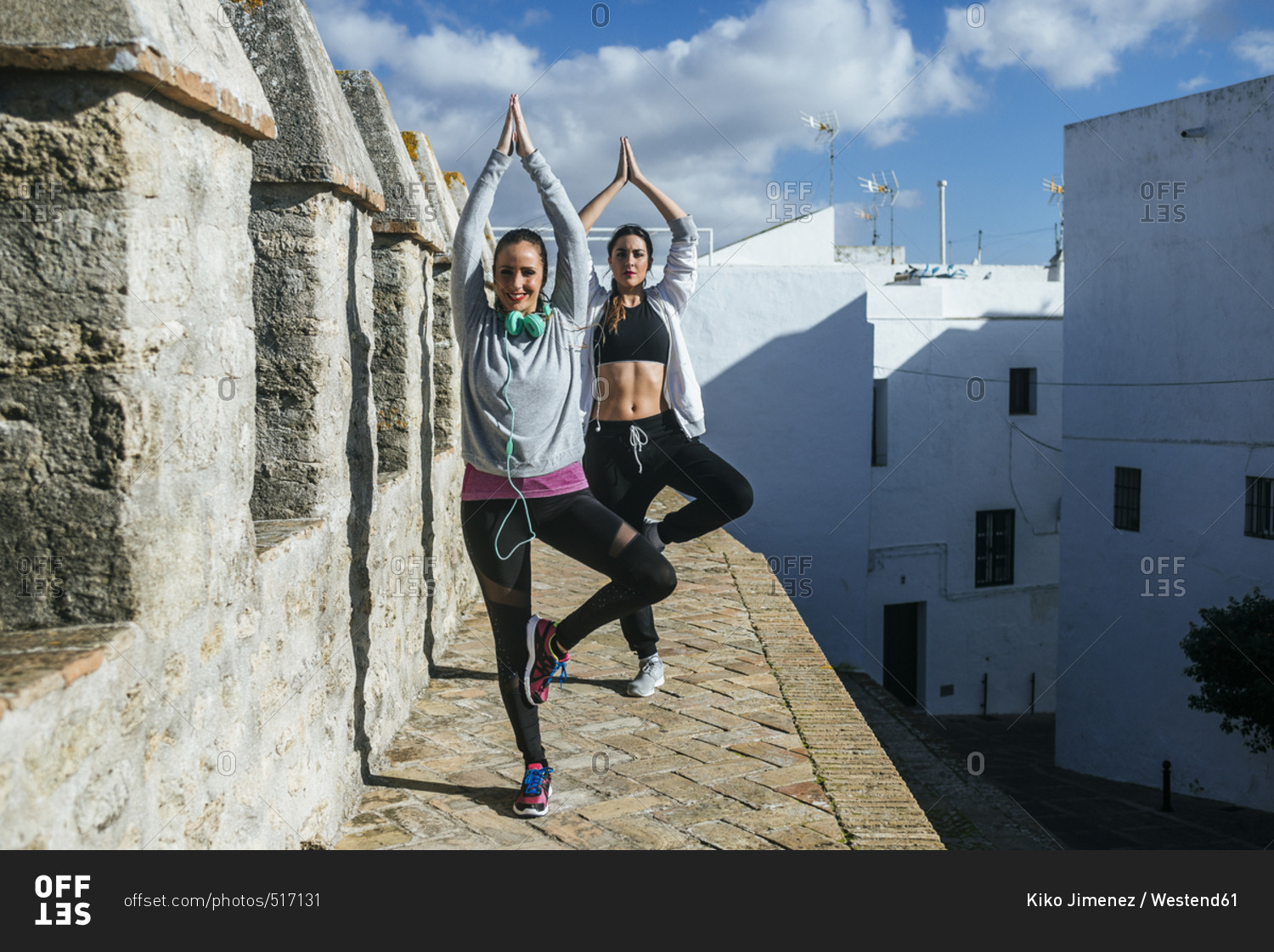 Two young women exercising yoga in the street
