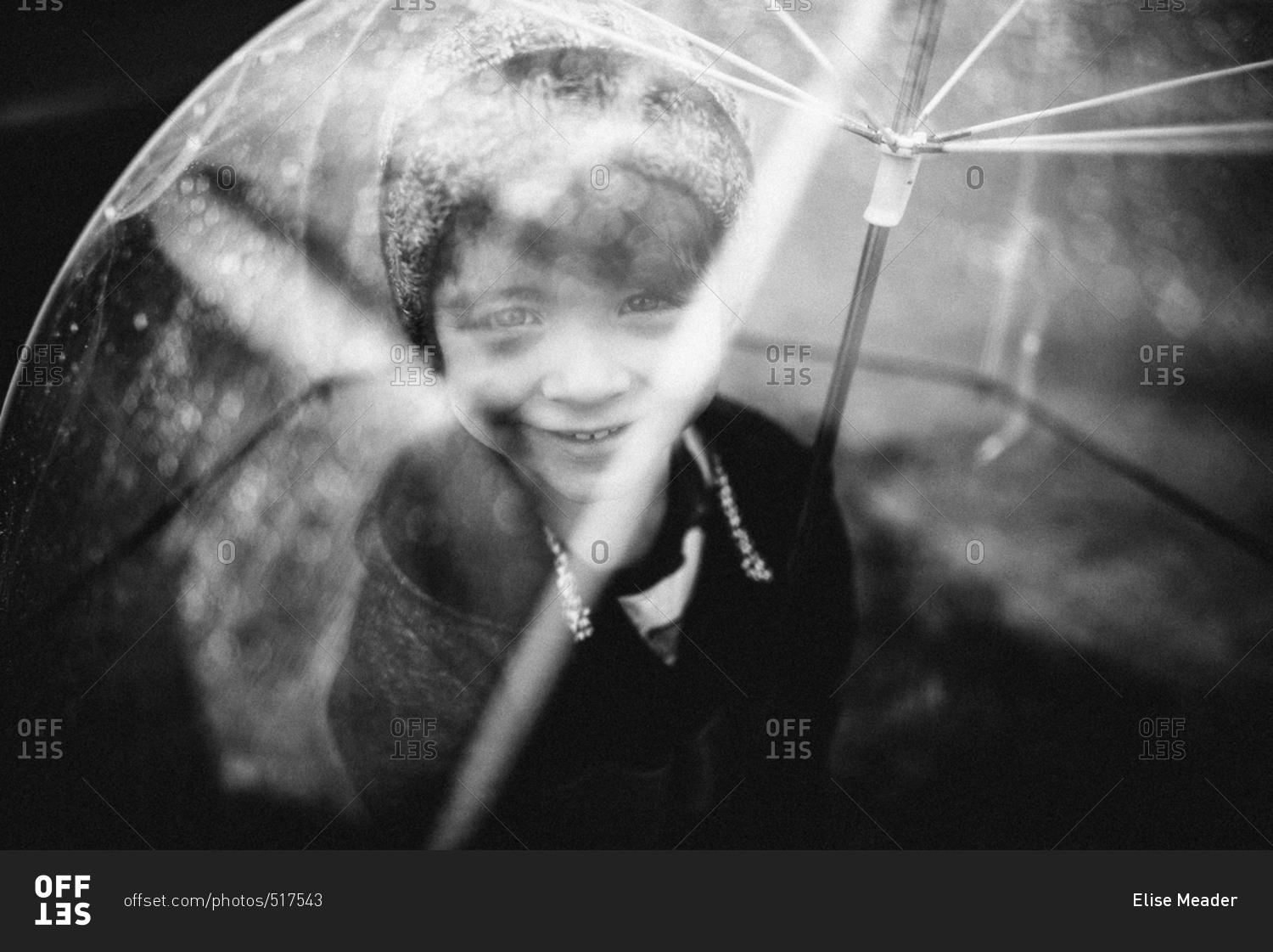 Young boy outside with clear umbrella in black and white