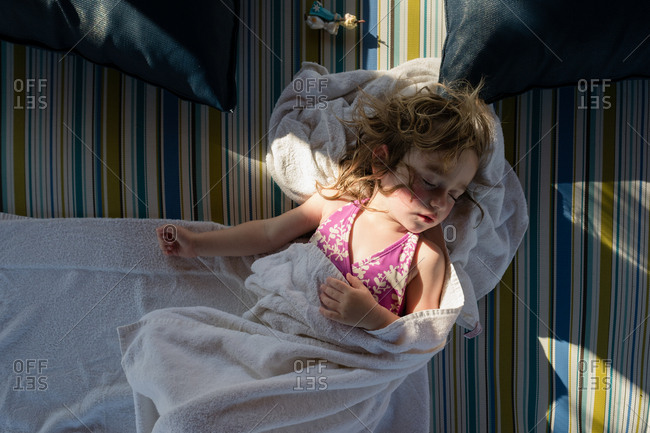 Young girl wrapped in towel, asleep on beach blanket