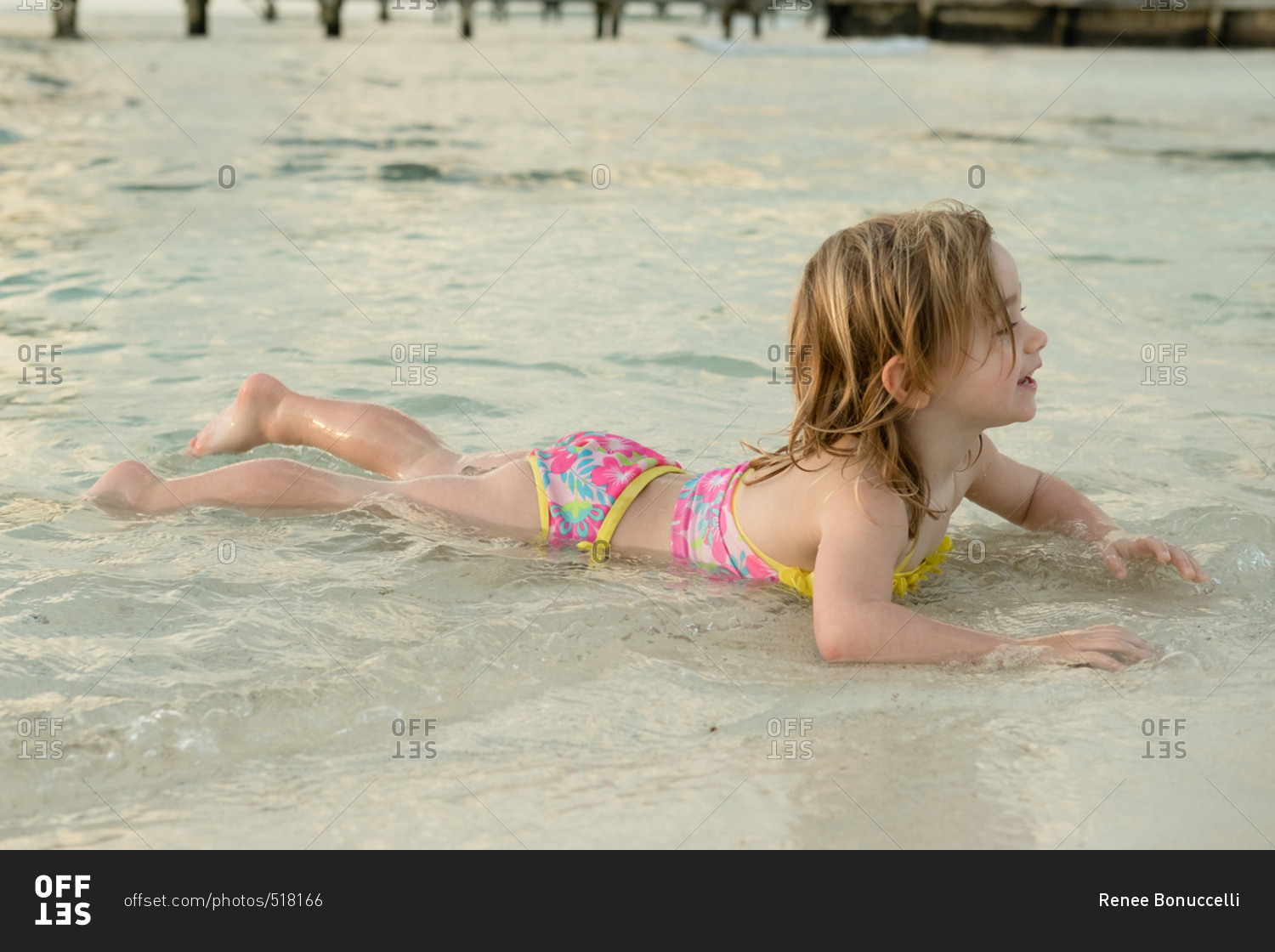 girl-lying-on-stomach-in-water-at-beach-stock-photo-offset