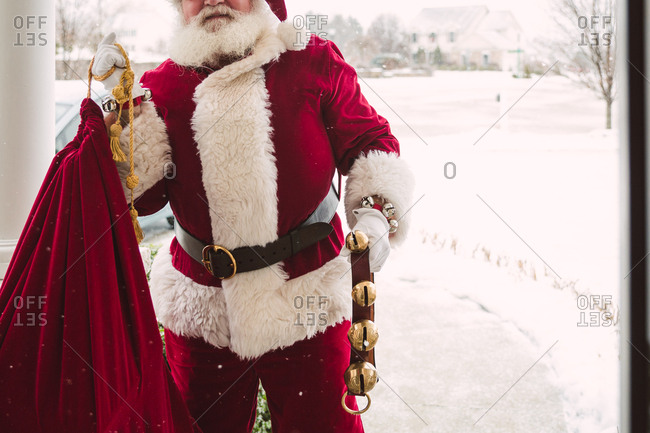 Santa Claus with bag of toys and sleigh bells on front porch