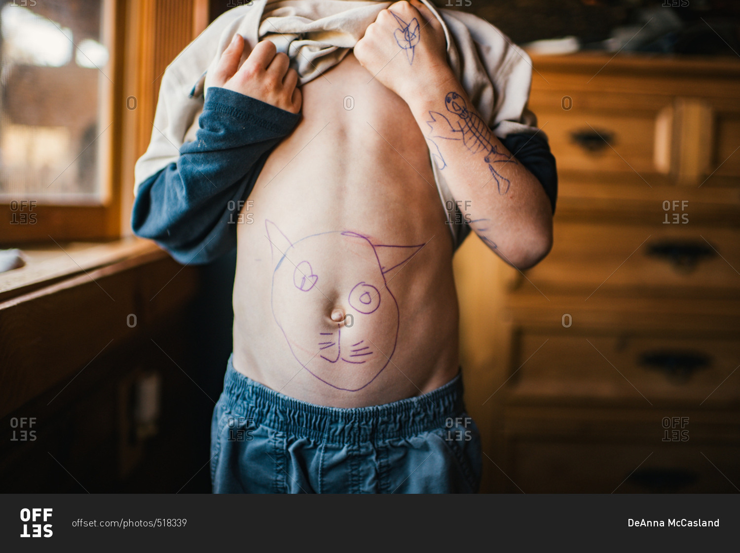 Boy lifting shirt to show cat drawing on his stomach