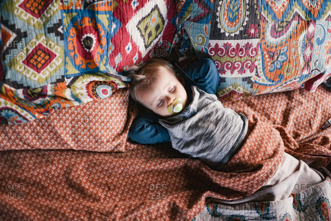 Overhead view of toddler boy sleeping in a bed