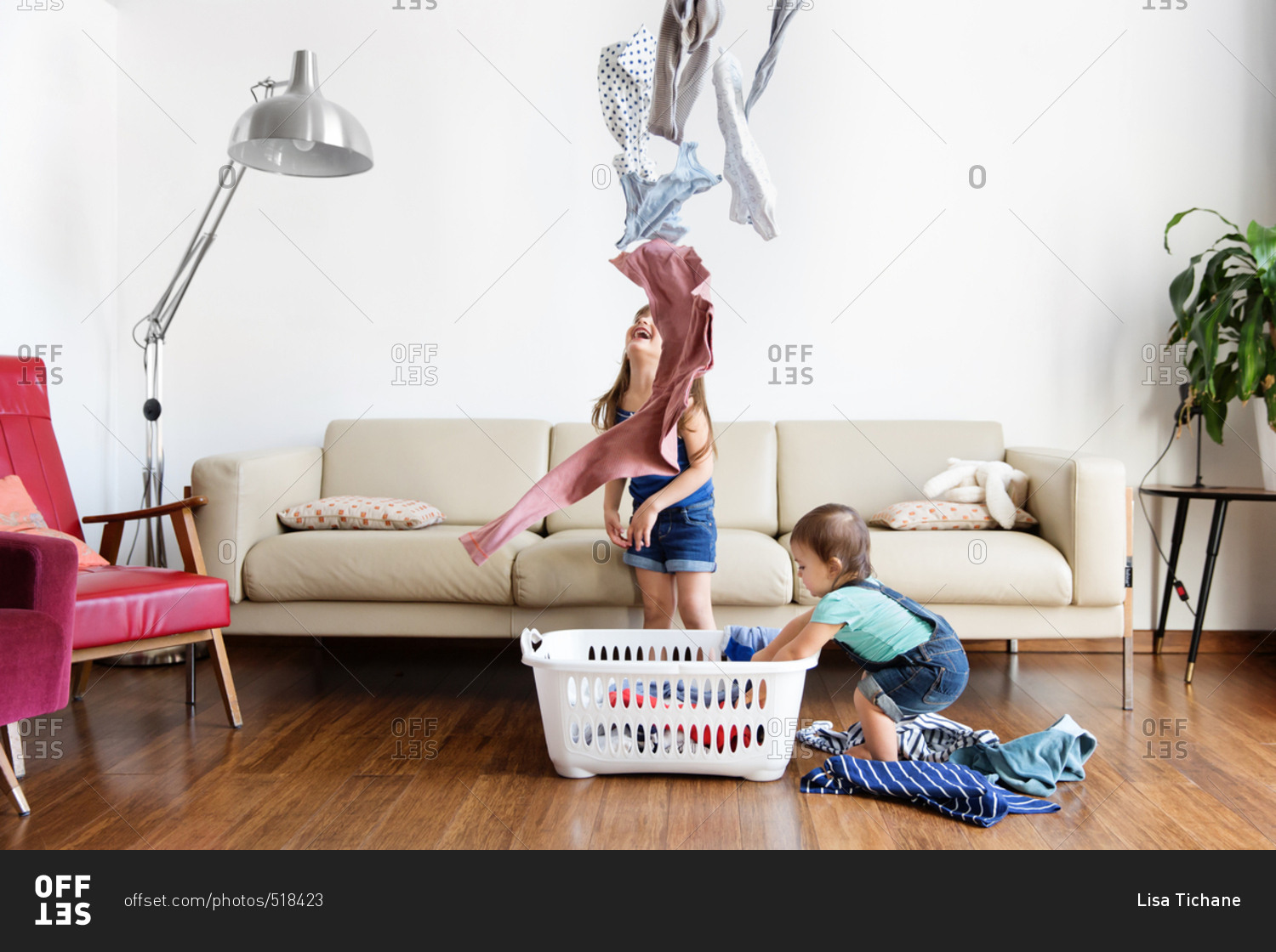 Girls throwing clothes out of laundry basket stock photo OFFSET