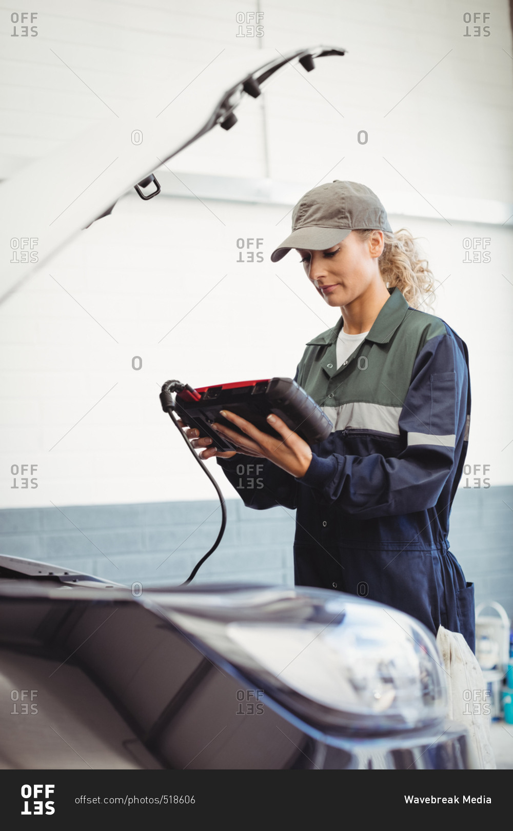 Female mechanic using electronic diagnostic device