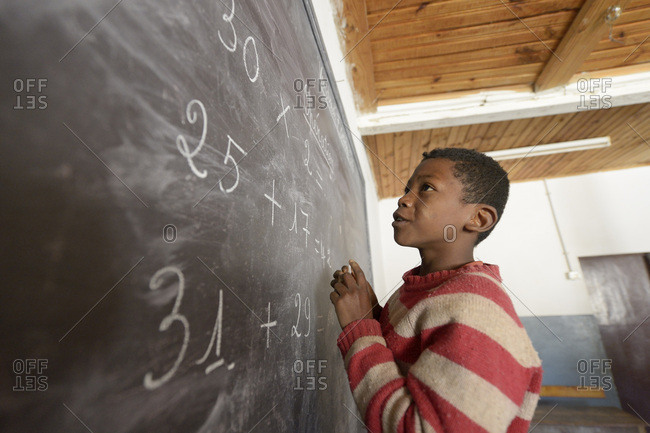 Madagascar- Boy in Fianarantsoa elementary school calculating at blackboard