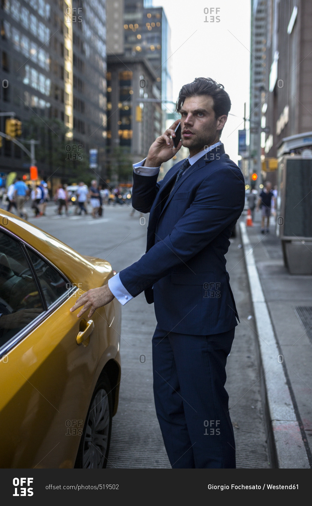 Businessman on the phone entering yellow taxi in Manhattan