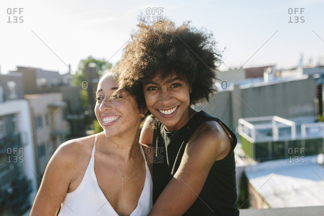 Female friends standing on rooftop- embracing