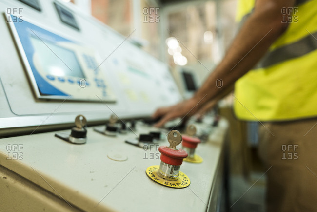 Worker in concrete factory pressing button on control panel