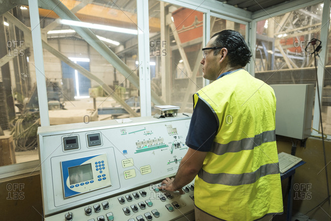 Worker in concrete factory pressing button on control panel