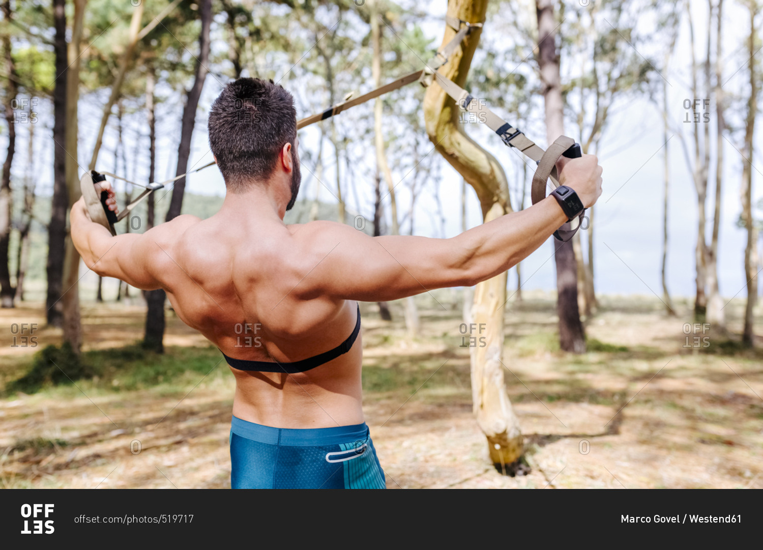 Bare-chested man doing suspension training outdoors