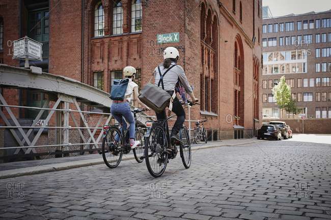 Germany- Hamburg- back view of couple riding electric bicycles at Old Warehouse District