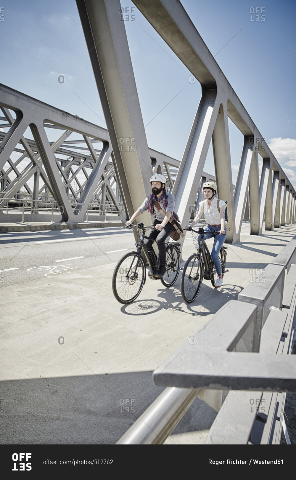 Germany- Hamburg- couple riding electric bicycles on a bridge