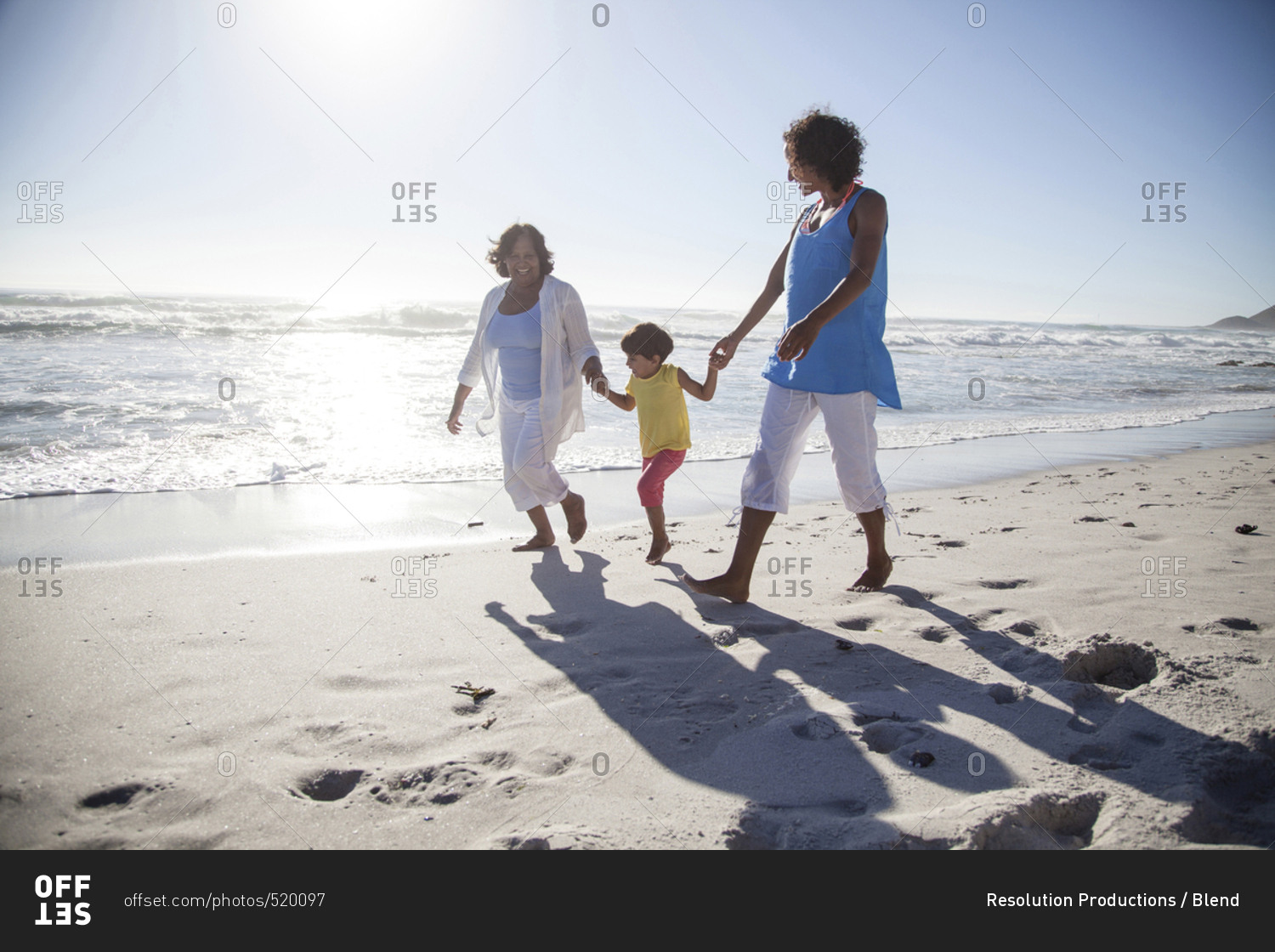 Mixed race grandmother, daughter and granddaughter walking on beach