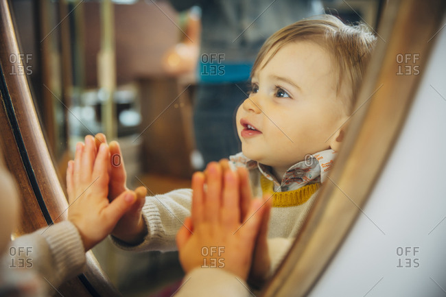 Caucasian baby boy standing at mirror