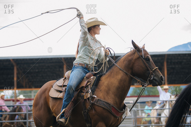 Caucasian cowgirl twirling lasso in rodeo