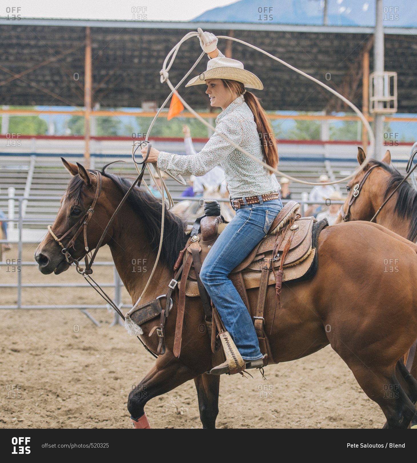 Caucasian cowgirl twirling lasso in rodeo stock photo OFFSET