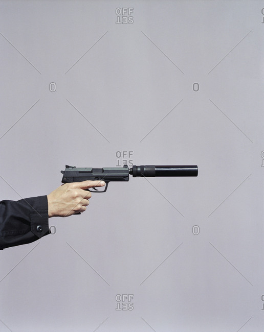 Detail of man aiming high powered hand gun with silencer