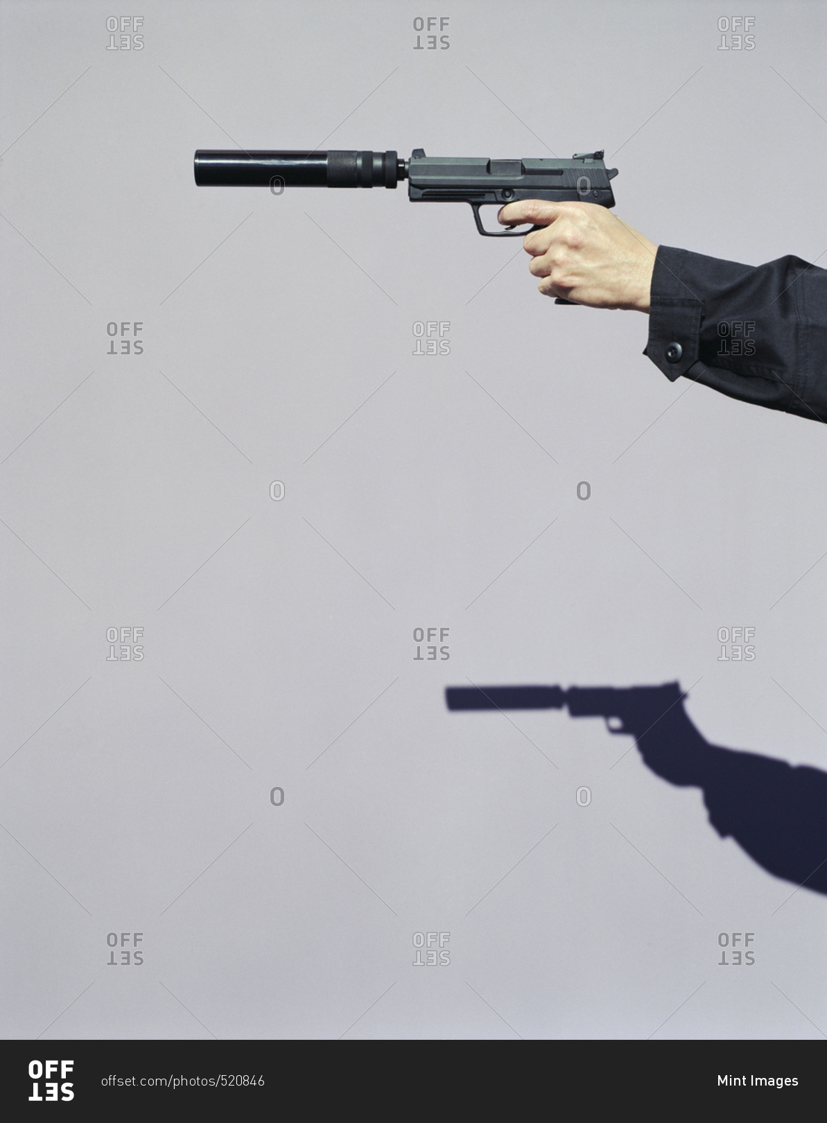 Detail of man aiming high powered hand gun with silencer