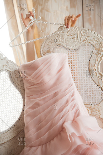 Hands of a woman holding a pink formal dress over a distressed screen