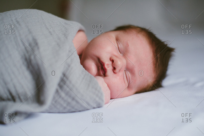 Infant boy wrapped in a muslin blanket sleeping