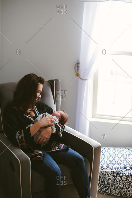Mother sitting in a chair in a nursery holding her newborn son