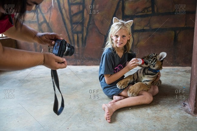 Kanchanaburi, Thailand - May 10, 2015: Girl feeding a baby tiger