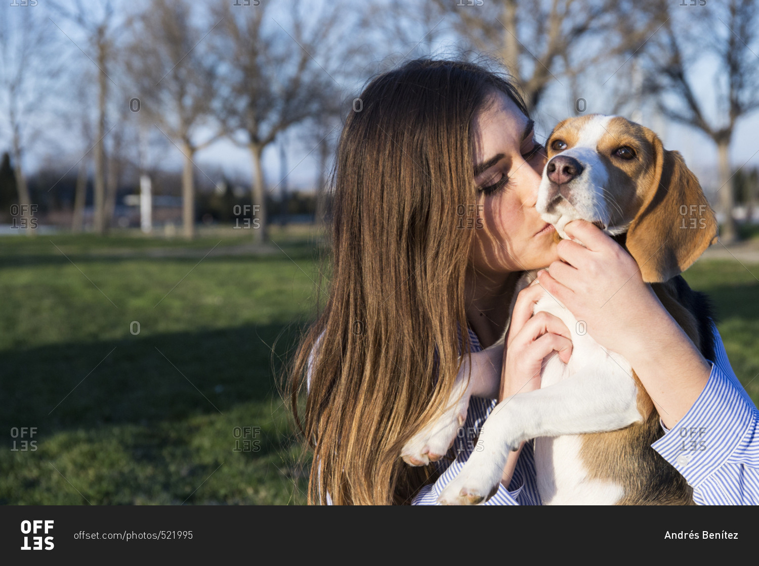 Beautiful woman kissing pet beagle in park