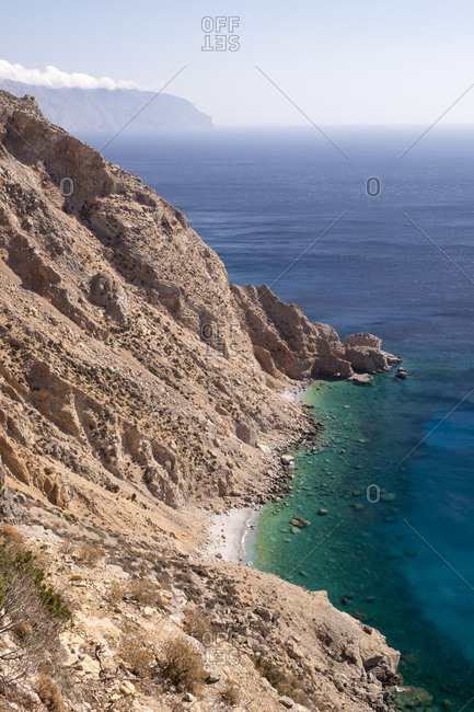 The turquoise and cerulean blue waters of the Aegean Sea at the base of a cliff.