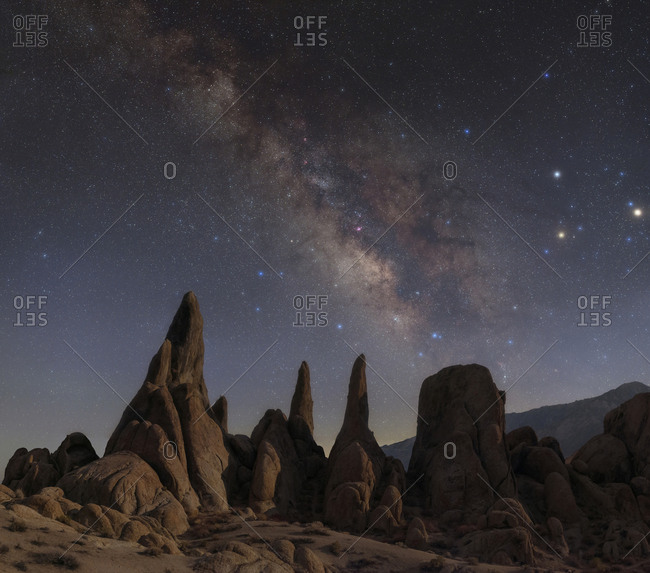 Bright galactic core of the Milky Way with Mars, Saturn, and Antares in Scorpius above moonlit sandstone rock formations in the Alabama Hills of California.