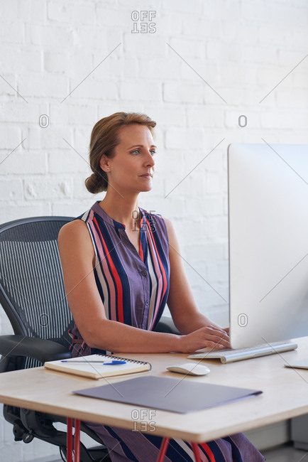 Female Executive Concentrating Working At Her Computer Sitting By