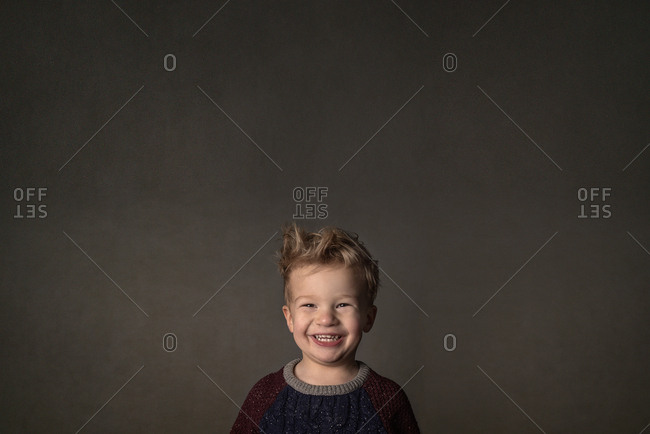 Blonde boy in a sweater with a big grin