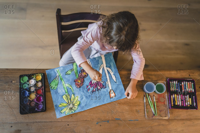 Little girl painting flowers at the table