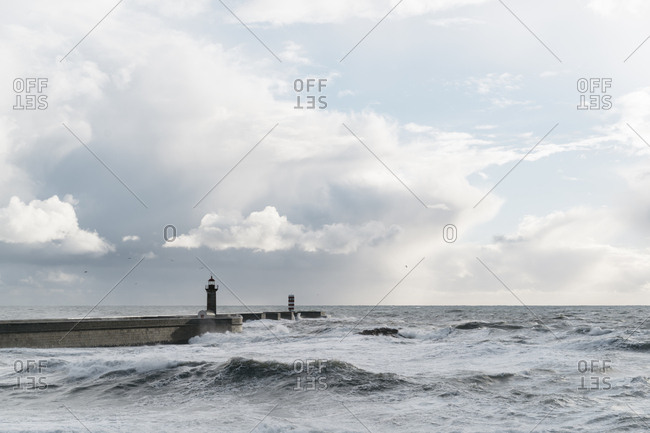 Waves crashing by a lighthouse near the Portuguese coast