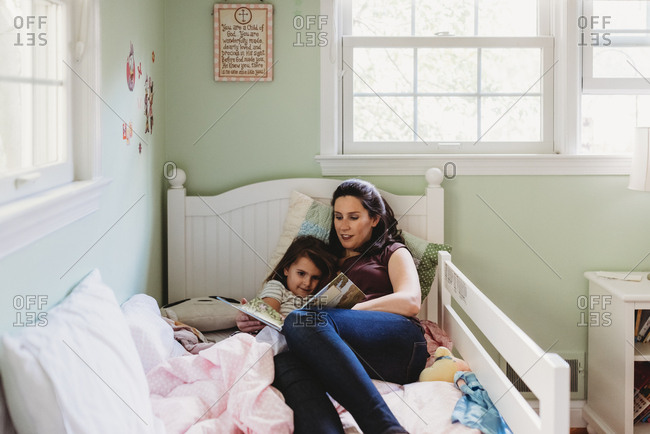 Woman lying in bed reading with daughter