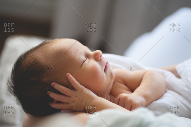 Sleeping newborn baby with hand against ear
