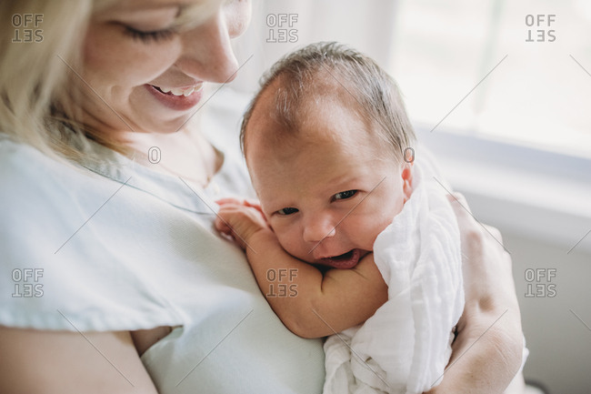 Woman holding yawning newborn baby
